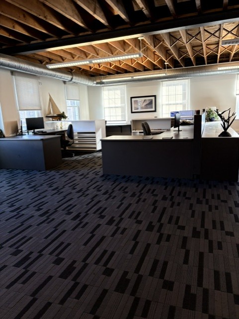 Wide view of the open office with desks, exposed beams, and ductwork