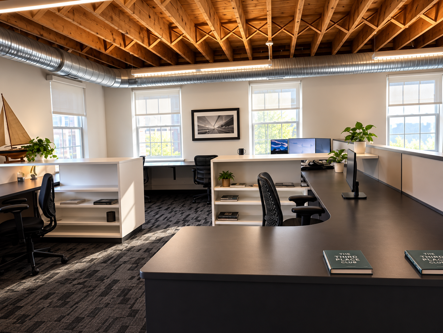 Open office at The Third Place Club with dark desks, white shelving, plants, and exposed wooden ceiling beams